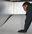 A contractor installing TerraBlock™ floor insulation in a Iron River crawl space