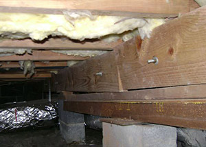 A sagging crawl space with concrete supports and wooden shimming a Crystal Falls crawl space