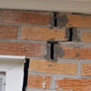 A brick wall displaying stair-step cracks and messy tuckpointing on a Escanaba home