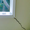 A long, diagonal crack that begins at a window corner of a Baraga home