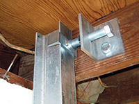 Securing the i-beam system to the top of the floor joist in a foundation wall repair in Iron River.