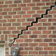 stair step cracking reaching from a window along the foundation wall in Marquette