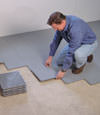 Contractors installing basement subfloor tiles and matting on a concrete basement floor in Ironwood, Michigan and Wisconsin