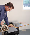 installing a waterproof vapor barrier on a basement floor to prepare for basement carpeting in a Escanaba home