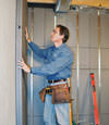 Insulated basement wall panels being placed against a concrete foundation wall in Hancock